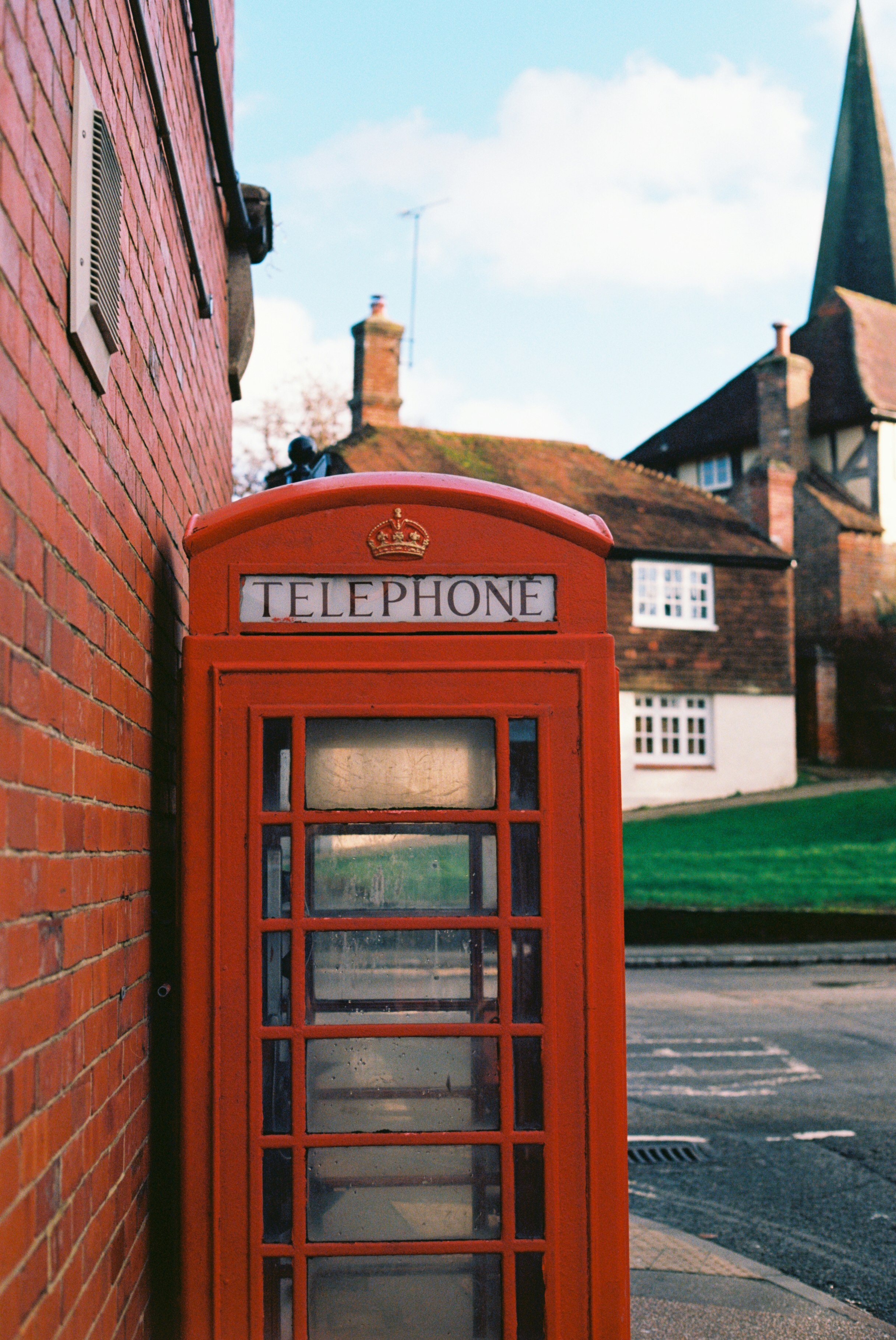 red telephone booth near brown brick building during daytime